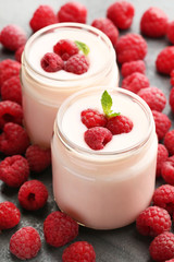 Raspberries yogurt in jars on wooden table