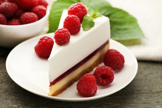 Tasty raspberry cheesecake in plate on wooden table