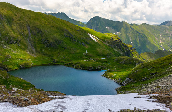 gorgeous view of lake in high mountains. lovely summer landscape with snow on grassy hills
