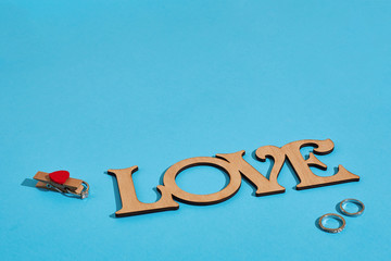 Wooden inscription Love and the ring on blue background. Marriage proposal. The concept of...