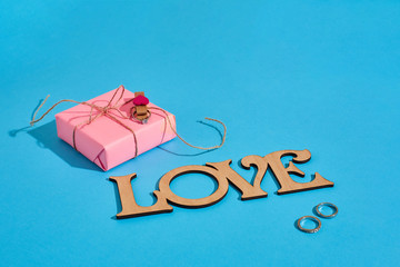 Wooden inscription Love, gift box and the ring on blue background. Marriage proposal. The concept...