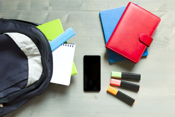 School and learning concept. Backpack with school supplies and smartphone