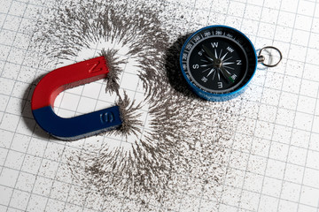 Red and blue horseshoe magnet or physics magnetic and compass with iron powder magnetic field on...