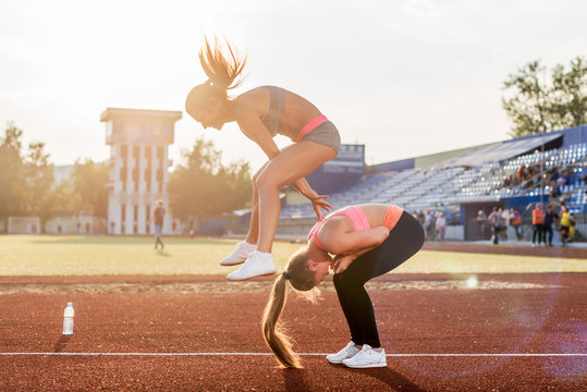 Fit Women At The Stadium Playing Leap Frog.