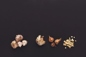 Whole and cut garlic on black isolated background