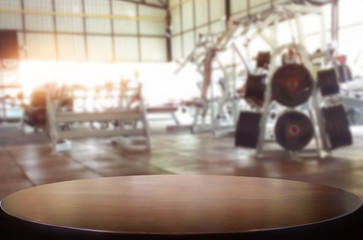 Wooden table on blurred background of fitness gym interior of modern club with equipment for your photomontage or product display.