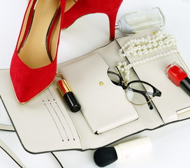 Female fashionable stylish accessories and cosmetics. red shoes with heels, white bag, watch, glasses, lipstick, mascara, red nail polish on a white background. Beauty blog concept. Copy space