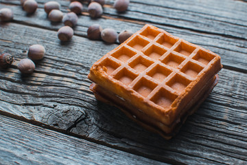 On wooden background are waffles, next to acorns and tangerines