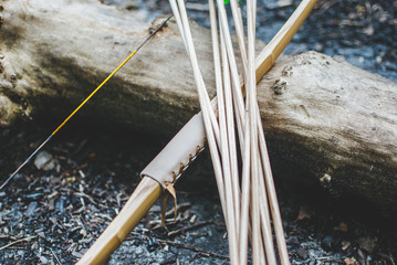 Traditional bow and wooden arrows laying on the log in the forest