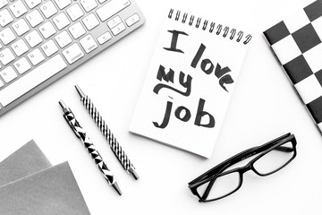 I love my job written in notebook at office desk on white background top view