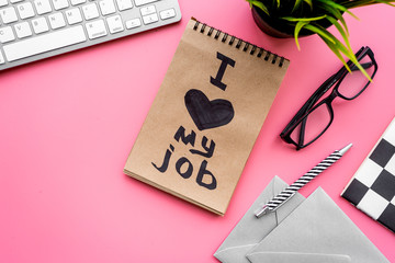 Find dream job. Handwritten motto I love my job in notebook on office desk on pink background top...