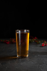 a glass of fresh grape juice and a branch with red berries on a dark background
