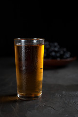 a glass of fresh grape juice and a bunch of juicy dark grapes on a dark background