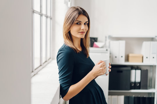 Young woman with cup of beverage in office