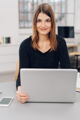 Young smiling woman sitting in front of laptop