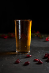 a glass of fresh grape juice and a branch with red berries on a dark background