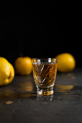 a glass with a drink, red berries, mint and yellow apples on a dark background