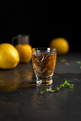 a glass with a drink, red berries, mint and yellow apples on a dark background