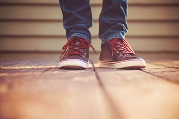 shoes on their feet outside on a stained wooden deck toned with a retro vintage filter instagram...