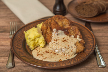 Rustic steak in breadcrumbs with mashed potatoes and white sauce grevi. 