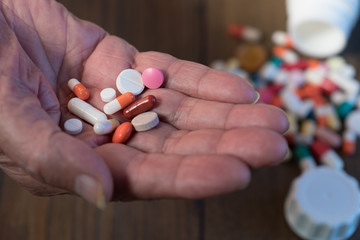 Colorful tablets in the hand of the pensioner. Pill in hand on dark background.