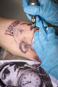 Detalle de tatuador realizando un tatuaje realista en un brazo