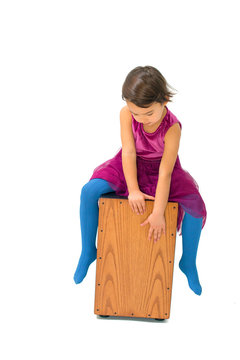 Little girl playing with a cajon isolated on white background