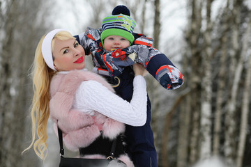 Young mother walks on a winter day with a baby in her arms in th