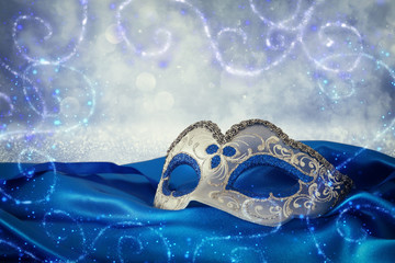 Image of elegant blue and gold venetian mask over blue silk fabric background.