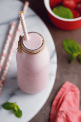 View from above on the strawberry smoothie in the glass bottle on a marble