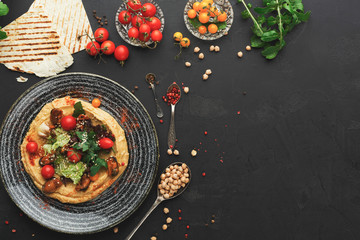 Hummus with vegetables and seafood on black background