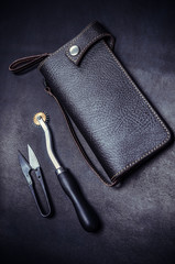 working tools, leather wallet on black background, top view.