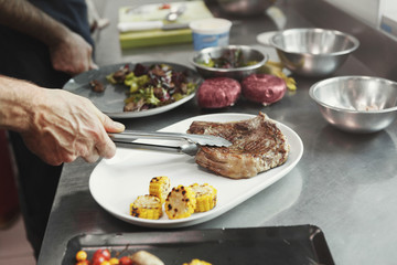 Chef cooking juicy beef steak at restaurant kitchen