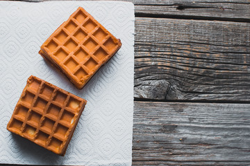 Waffle on a wooden background on a white napkin