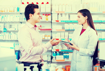 Pharmacist and consulting man in pharmacy