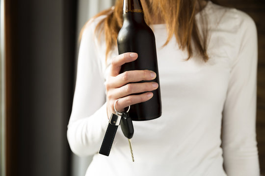 Do not drink and drive concept. Woman holding bottle of beer and car keys in hand