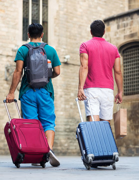 Men tourists walking with suitcases