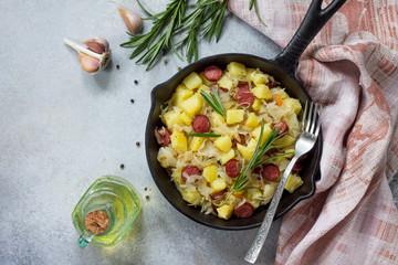 Homemade snacks on a stone or slate background. Warm salad with potatoes sauerkraut and smoked sausages. Flat lay. Top view with copy space.