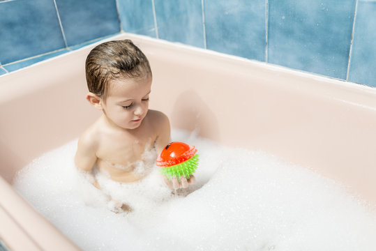 Child playing with a ball in a bubble bath