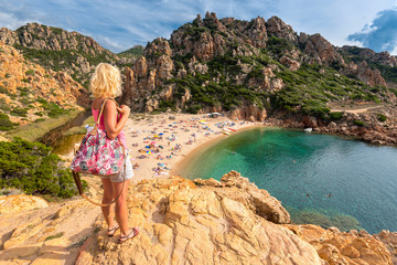 Young blonde woman looking at Li Cossi beach (Spiaggia di Li Cossi), Costa Paradiso, Sardinia, Italy