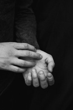 black and white photograph of man's hands on a black background