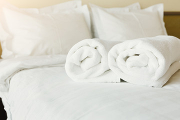 Fototapeta na wymiar White towels on bed in hotel bedroom closeup