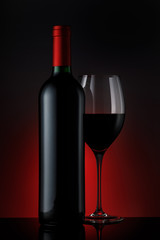  Bottle of red wine with a glass on a black background, vertical close-up image