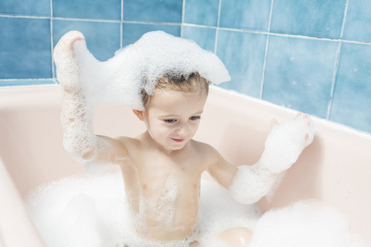 Child in the bath with his head full of foam.