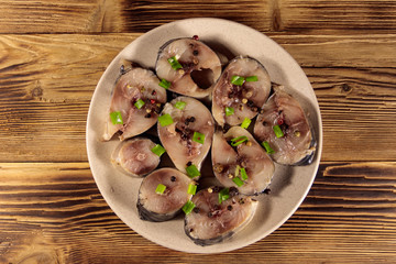 Sliced mackerel with spices on wooden table. Salted scomber on a plate