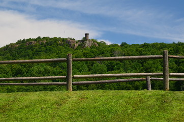 Fototapeta na wymiar A view of a tower on a mountain and split rail fence