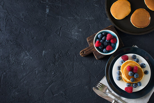 Homemade pancakes stack with berries over black texture
