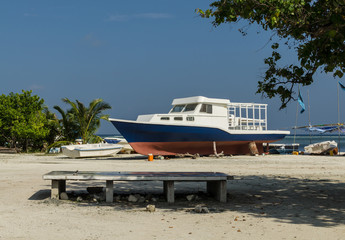 Close-up: colorful boat lying on the beach of  tropical island, against a bright blue sky and turquoise water,  tropical island, Maldives, Indian Ocean