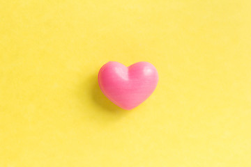 Obraz premium Red heart shape over yellow table. Valentines day symbol for background use. Love, romance, and passion.