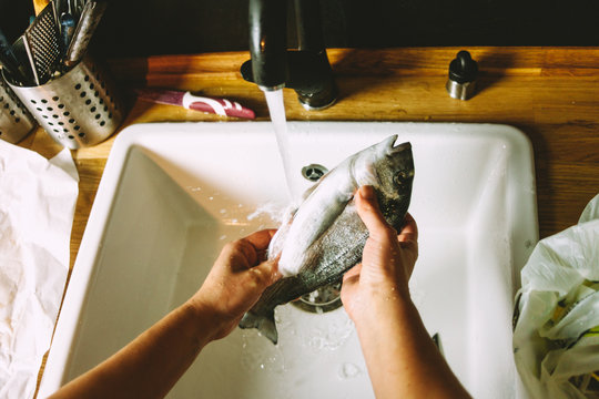 Cooking a fresh gilthead seabream with lemon, garlic and herbs, covered with salt